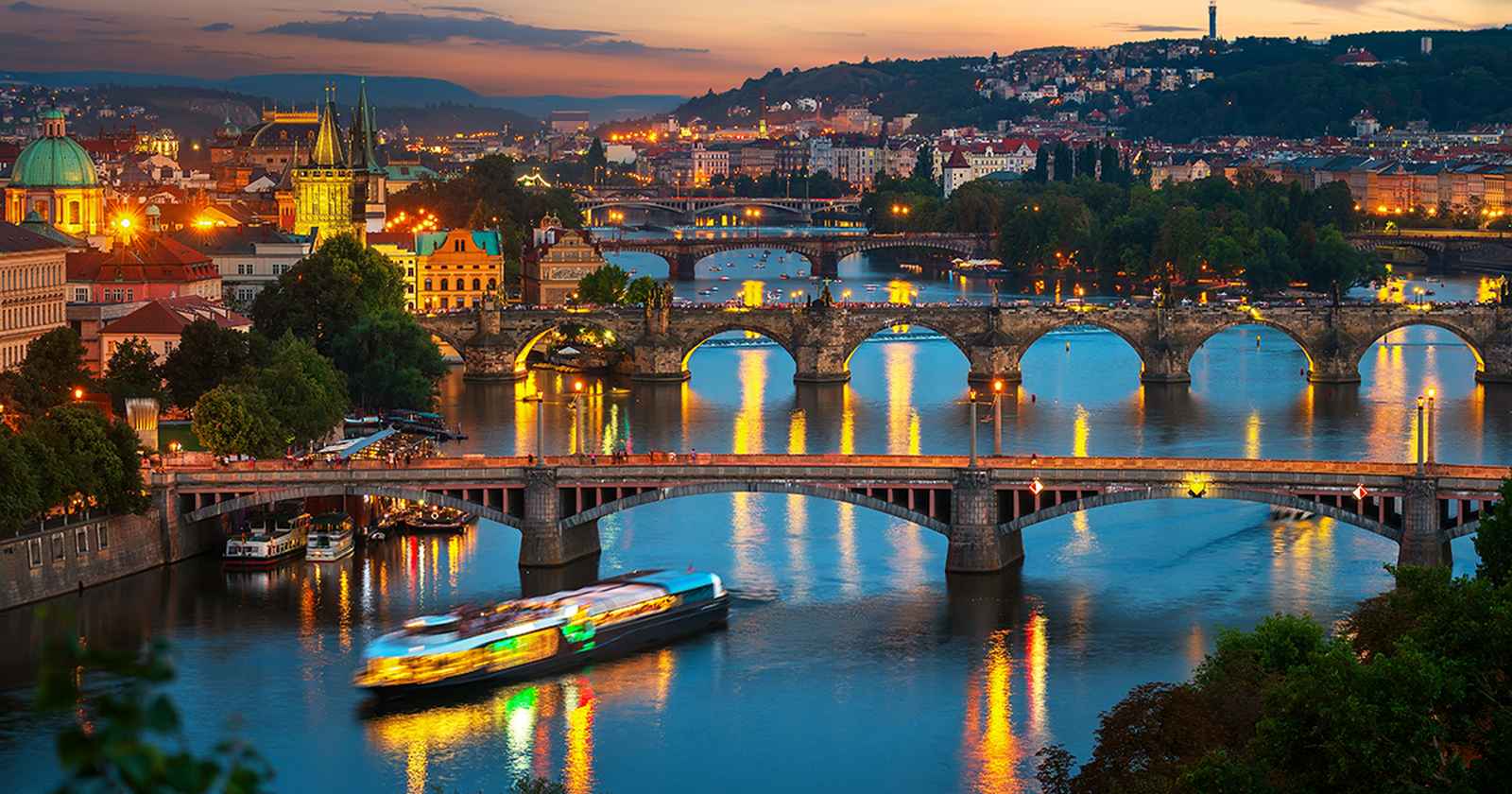 Vltava river bridges at dusk with cruise boat