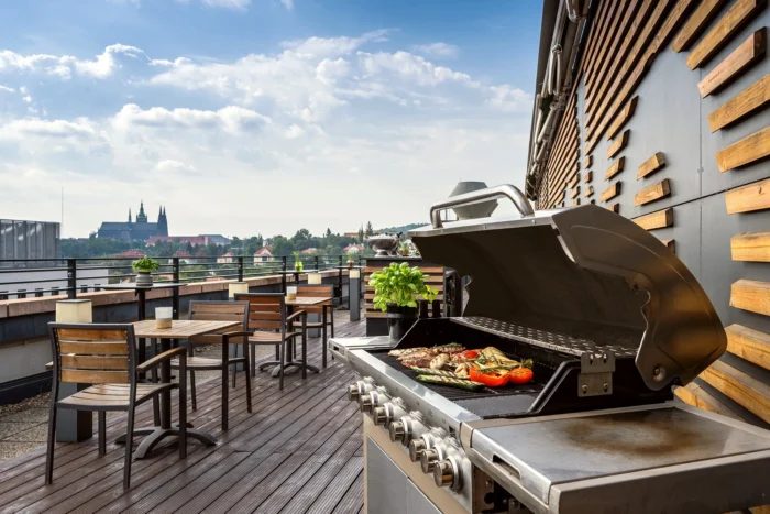 The Diplomat rooftop terrace at golden hour — timber decking, bar tables, and a clear view of Prague Castle.